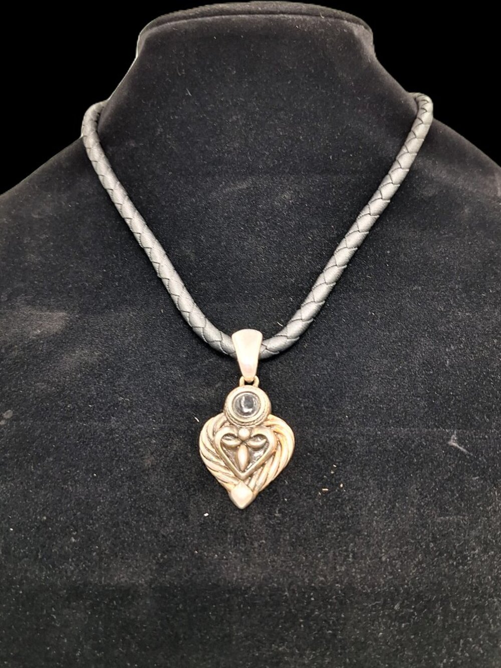 Silver tone pendant on braided leather cord